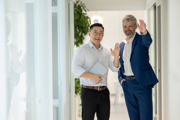 istock Men walking along corridor in office and talking about their work, waving hands, greeting partners. 1578298028
