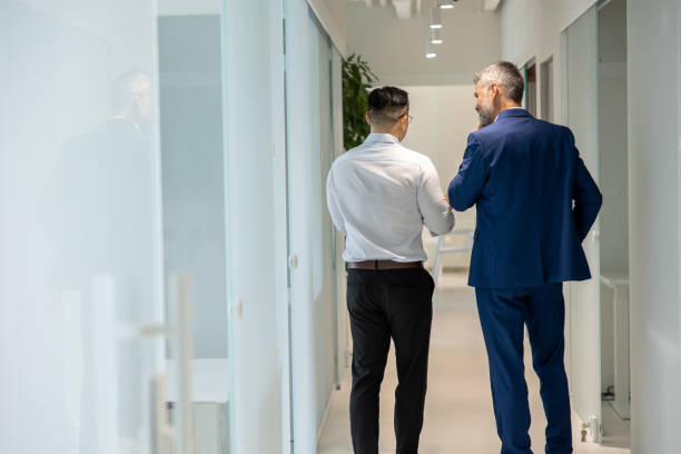 istock Men walking along corridor in office and talking about their work. 1578298033