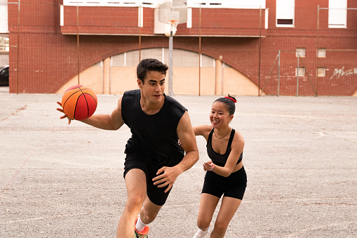 A dark-haired, muscular boy plays basketball with his Chinese friend photos of young girls of different races playing sports