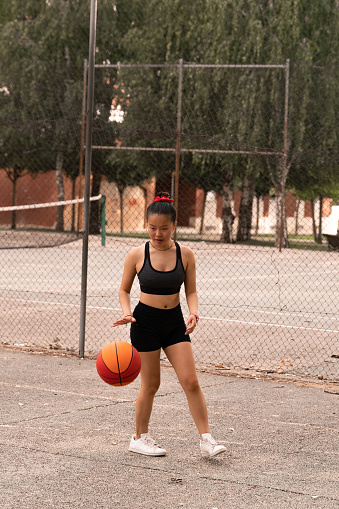 A Chinese girl playing basketball- she plays with her Chinese friend during the summer.