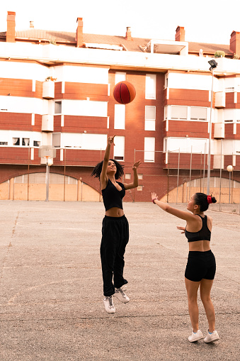 A Latina girl playing basketball- she plays with her Chinese friend during the summer.