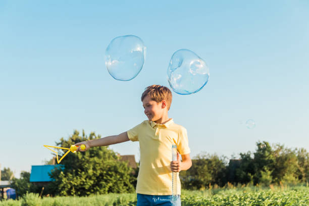 istock Caucasian boy launches big soap bubbles on a sunny summer day outdoors. Active leisure, happy childhood. 1578308297