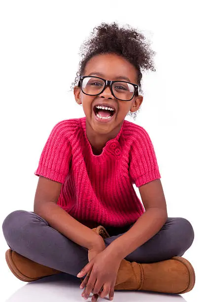 Photo of Cute young African-American girl sitting on floor smiling