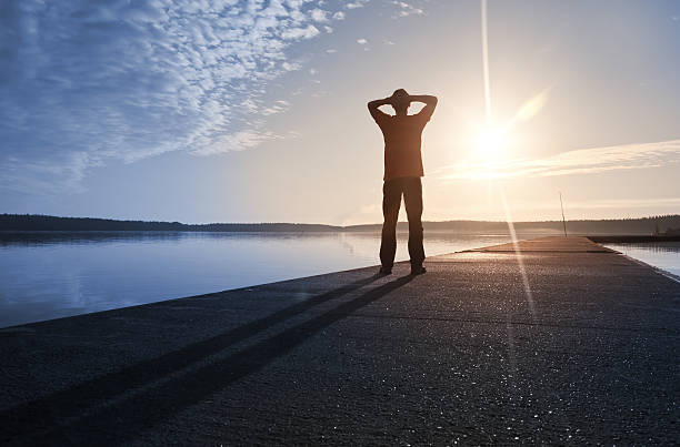 Man stands on the concrete pier starring at Sun