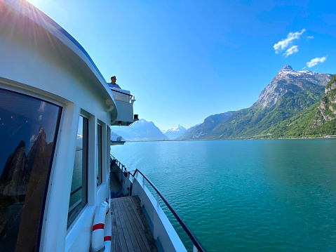Passenger ship named Weggis with captain on the bridge on Lake Lucerne on a sunny spring day with Swiss Alps in the background. Photo taken May 22nd, 2023, Sisikon, Switzerland.