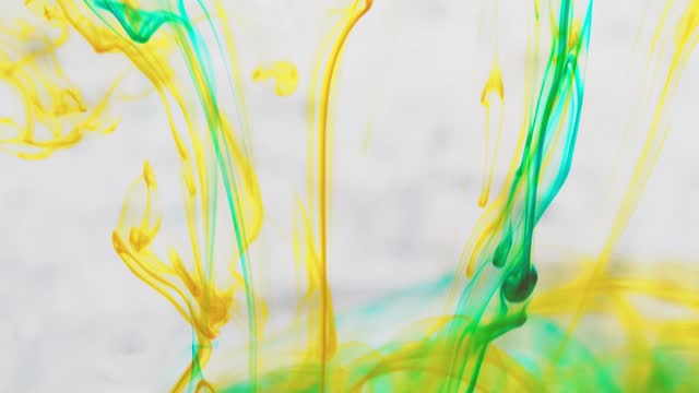 Multicolored inks spreading in water, forming whimsical patterns and iridescent hues of diverse shades. yellow and blue color