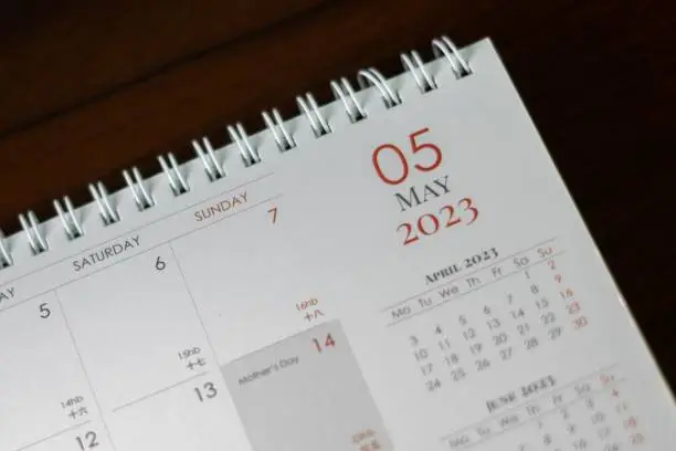 This close-up image features a desk with a calendar on top, surrounded by a modern office setting