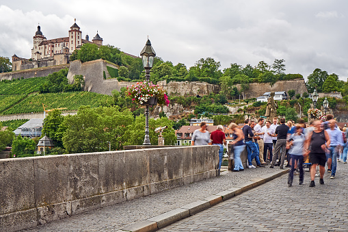 Wuerzburg, Germany - July 28, 2023: Crowd on the old Main Bridge. Marienberg Fortress in the background.
