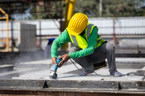 Labor man cutting steel at the construction site. Heavy Industry Manufacturing Factory. Prefabricated concrete walls. Asian worker wearing safety hardhat helmet