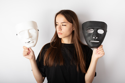 mood swings, from happiness to depression, mental health problems, a teenager with a black and white mask, a young woman actress chooses a role for a performance