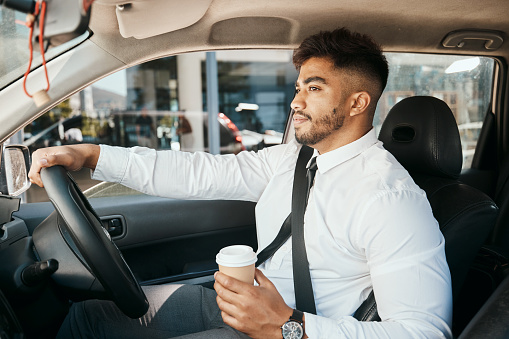 Business man, coffee cup and driving car for morning commute, transportation and waiting in traffic. Corporate indian male employee, travel and driver at steering wheel for journey on road with drink