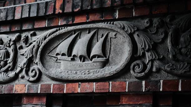 A large brick wall is adorned with a mural of a vast ship sailing into the horizon
