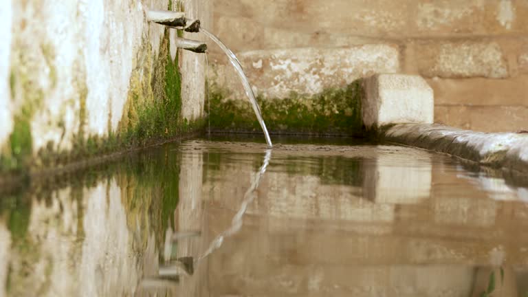 Clear and crystalline water comes out of a public fountain in the town of Castellote, Teruel, Aragon, Spain, Maestrazgo, beautiful reflections in the water, it functioned as a trough