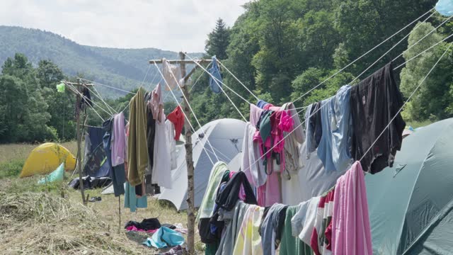 Clothes dry by hanging from laces outdoors outside the campground. The video presents a tent camp where young people keep unforgettable memories of summer adventures and inspiring landscapes.