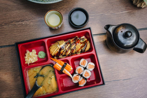 Table top view of bento box with salmon rolls and miso soup  at the restaurant.