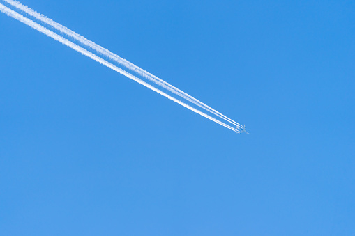High flying airplane with vapor trail against clear sky, Berlin Schönefeld