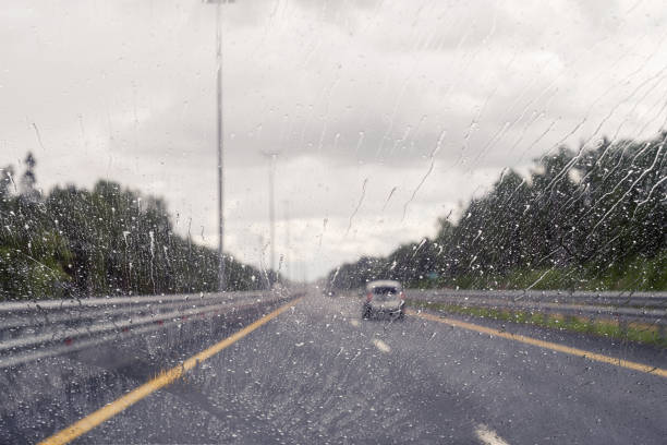 istock Road view through windshield car window with going rain drops during driving at speed. Unfocused highway. Autumn 1578545393