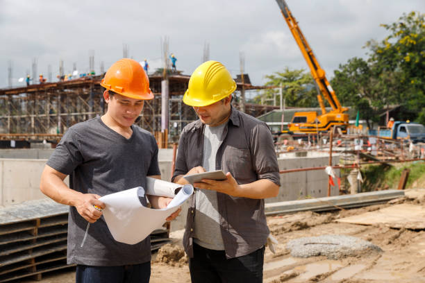 istock Team of construction workers discussing project details with blueprint in construction site. 1578547735