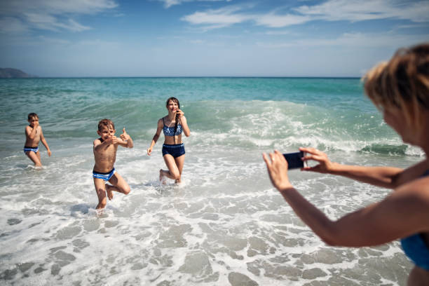 istock Mother with three kids playing in waves on the sunny summer day 1578549404