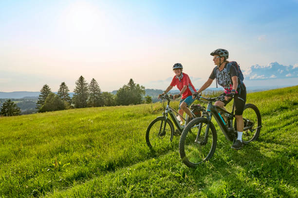 two senior women ciycling with e bikes in the german alps - german countryside imagens e fotografias de stock