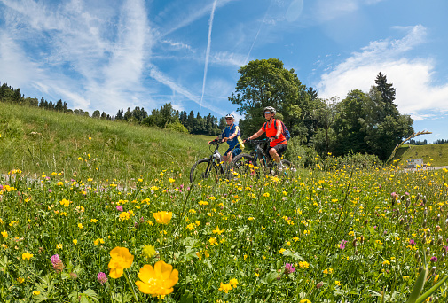 two senior girlfriends having fun during a cycling tour in the Allgau Alps near Oberstaufen, Bavaria, Germany