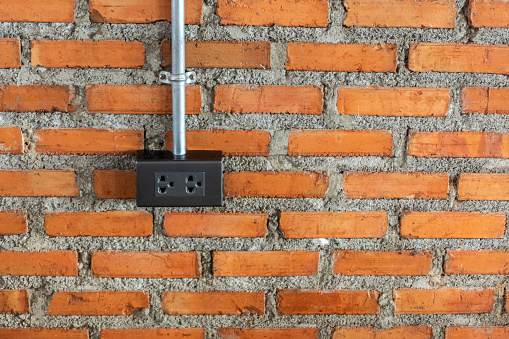 Electric plug on red brick wall