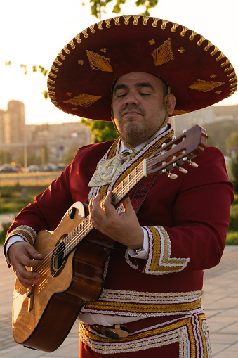 Mexican musician mariachi plays the guitar on a city street