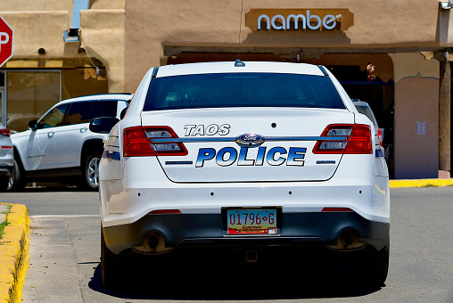 Taos, New Mexico, USA - July 24, 2023: A Taos Police cruiser waits to turn left in the Taos Plaza on a hot, summer afternoon.