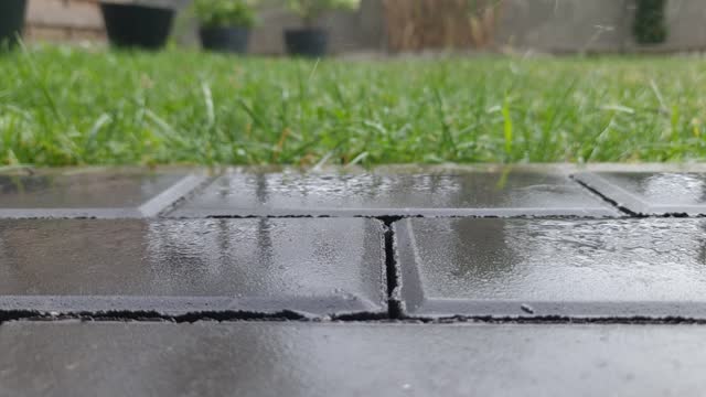 Drops of heavy rain on sidewalk surface in garden