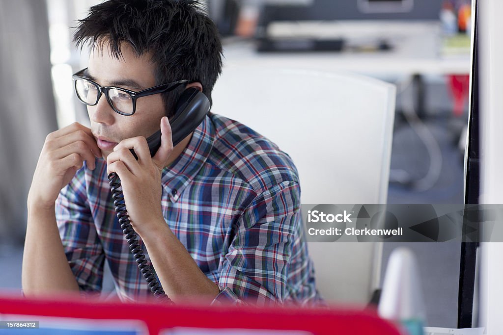 Uomo d'affari a parlare al telefono in ufficio - Foto stock royalty-free di Ufficio