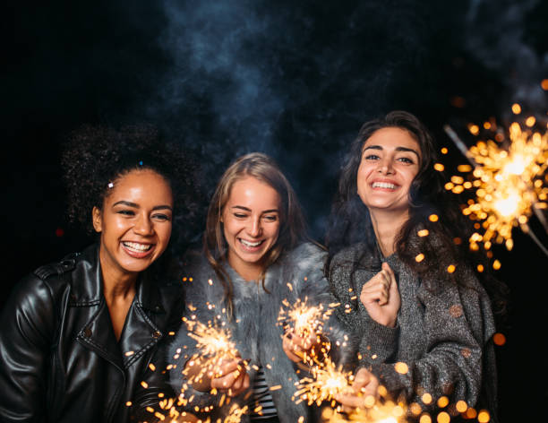 istock Three young women laughing at night and holding sparklers 1578656369