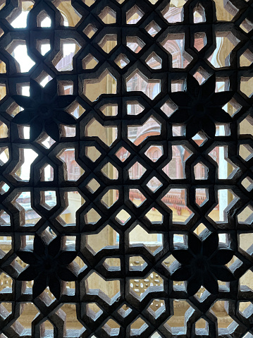 Stock photo showing close-up view of historic Indian jali window screen architectural decoration. These screen were designed for privacy and security whilst allowing light to enter a room as well as the free movement of air for ventilation.