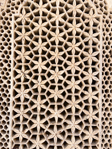 Stock photo showing close-up view of historic Indian jali window screen architectural decoration. These screen were designed for privacy and security whilst allowing light to enter a room as well as the free movement of air for ventilation.