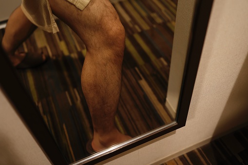 One Asian man's hairy shins in the mirror.