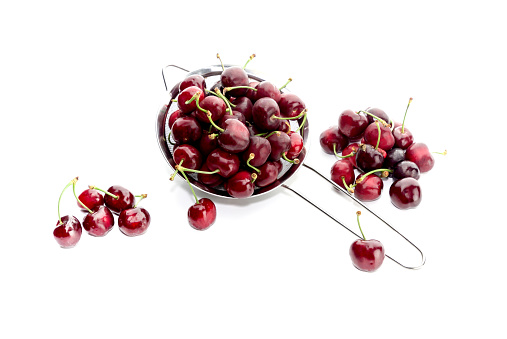 Ripe, red cherries on a sieve close-up on a white background