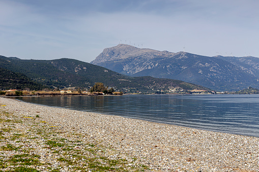 Seascape. View of a deserted beach with pebbles sea and mountains (Greece, Peloponnese) on a sunny day