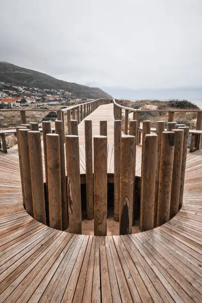Boardwalk with wooden roundabout in Quiaios Beach connecting to the village and mountain in the background