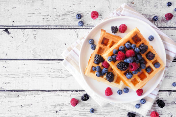 Breakfast waffles with raspberries and blueberries. Overhead view table scene.