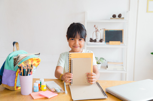 Pupil child put books and notes into backpack. School supplies.Back to school concept. Kid prepare for studies. Portrait cute little girl packing backpack .