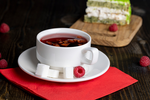 Red raspberry tea with pieces of fruit and berries, pieces of fruit float in the tea, including very small ones