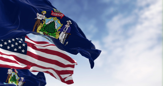 Maine state flags and the United States national flag waving in the wind on a clear day. 3d illustration render. fluttering fabric. Selective focus