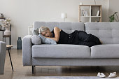 Calm homeowner woman lying on side on comfortable sofa