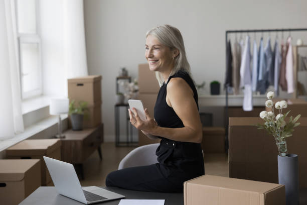 istock Happy mature entrepreneur lady using mobile phone at workplace 1578906154