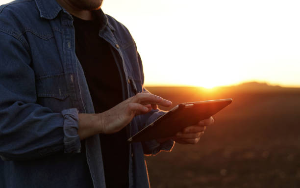Cropped shot of male farmer's hands use digital tablet on plowed field for control of soil quality, land readiness for sowing crops and planting vegetables. Smart farming technology and agriculture. la toma recortada de las manos de un agricultor masculino usa una tableta digital en el campo arado para controlar la calidad del suelo, la preparación de la tierra para sembrar cultivos y plantar hortalizas. tecnología agrícola inteligente y agricultur