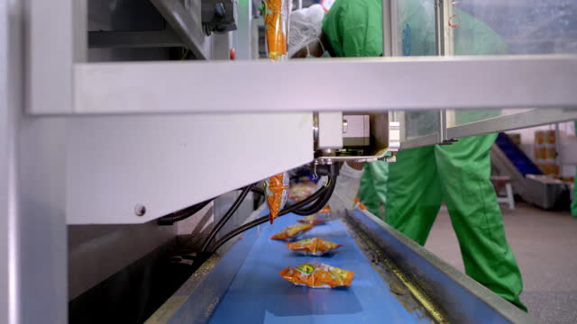 Corn snacks are progressing along the conveyor belt within the packaging department.