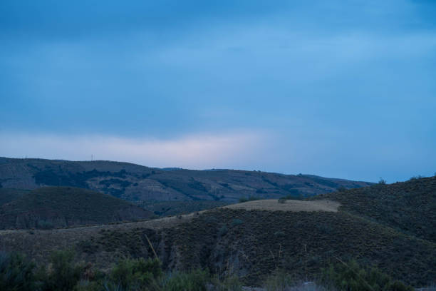 Dawn in the south of Granada, it is a mountain area, there is vegetation on the mountain, the sky is cloudy