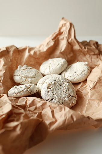 French fragile beige meringue cookies with cracks served on a brown craft paper. Appetising crispy homemade pastries for holiday party.