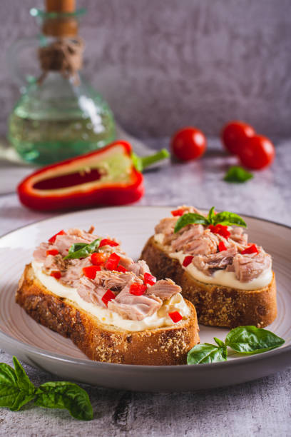 istock Open sandwiches with canned tuna, pepper and basil on cream cheese on a plate vertical view 1579115909