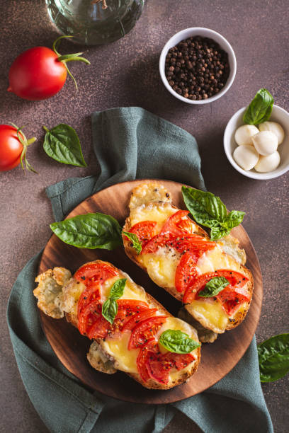 istock Baked brioche sandwiches with tomatoes, mozzarella and basil on a board top and vertical view 1579136534