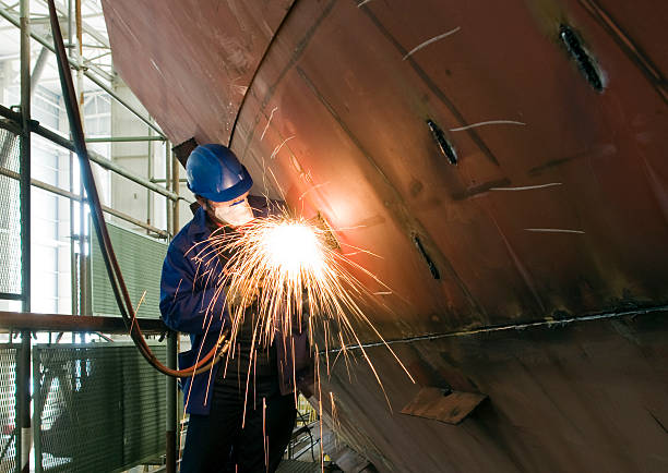 Metalworker Welding new steel plates on a ship's hull during repair work on a ship in a dry dock. industrial ship stock pictures, royalty-free photos & images